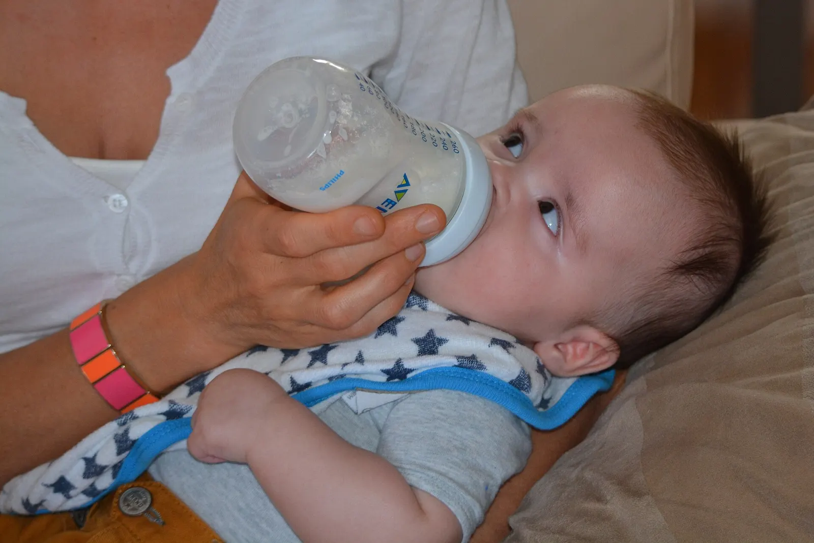 Baby being bottle-fed in someone's arms